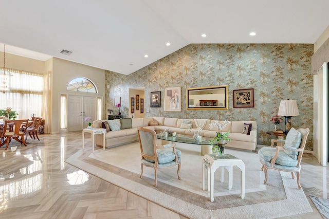 living area featuring visible vents, baseboards, high vaulted ceiling, and wallpapered walls