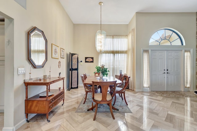 dining space with baseboards, a notable chandelier, and a towering ceiling