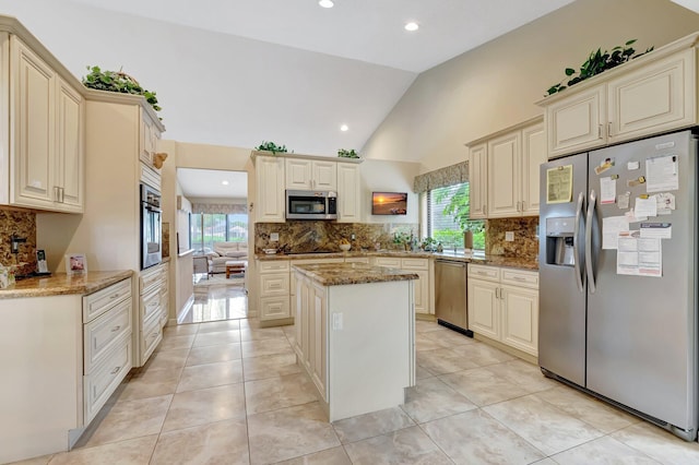 kitchen with appliances with stainless steel finishes, stone counters, cream cabinetry, and a center island