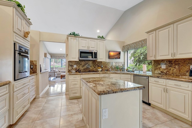 kitchen featuring a kitchen island, stainless steel appliances, vaulted ceiling, and light tile patterned flooring