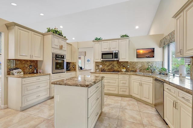 kitchen with a center island, light stone counters, a sink, appliances with stainless steel finishes, and backsplash