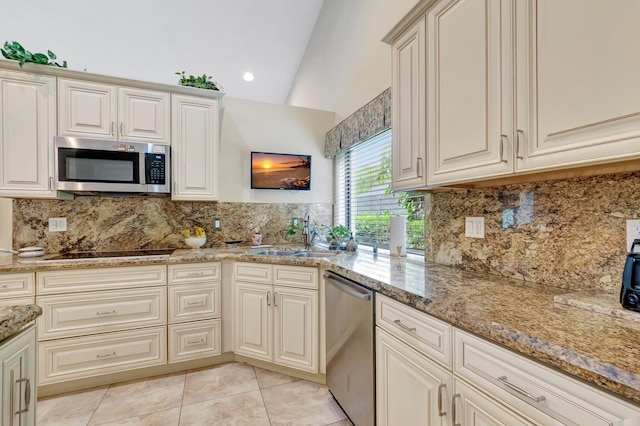 kitchen featuring decorative backsplash, appliances with stainless steel finishes, a sink, lofted ceiling, and light tile patterned flooring
