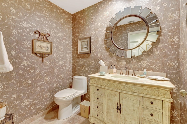 bathroom with vanity, wallpapered walls, toilet, and visible vents