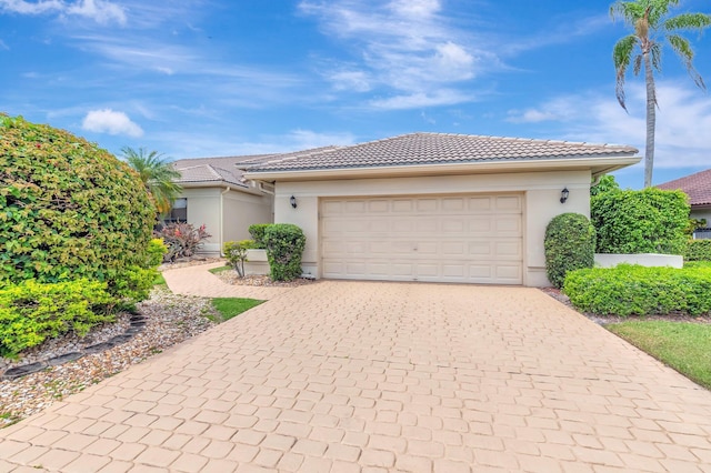 view of front of home with an attached garage, decorative driveway, stucco siding, and a tile roof
