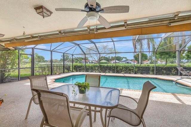 pool featuring glass enclosure, a ceiling fan, and a patio area