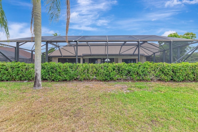 back of property with glass enclosure and a yard