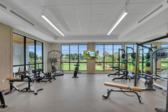 gym with a paneled ceiling and a tray ceiling