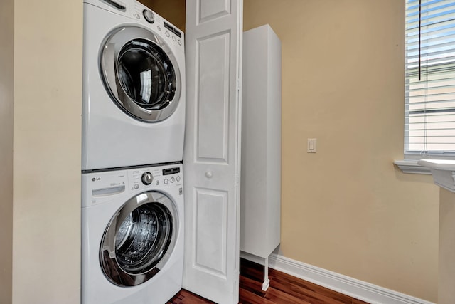 112 Osceola Ln, Jupiter, FL 33458 - clothes washing area with baseboards, stacked washer and clothes dryer, laundry area, and dark wood-type flooring