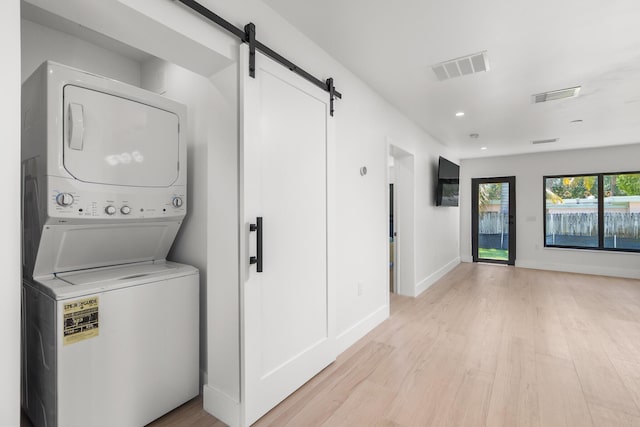 303/305 De Carie, Delray Beach, FL 33444 - clothes washing area with laundry area, a barn door, light wood finished floors, stacked washing maching and dryer, and visible vents