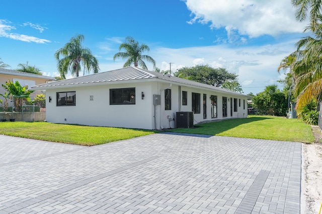 303/305 De Carie, Delray Beach, FL 33444 - ranch-style house featuring central AC, a front lawn, stucco siding, a standing seam roof, and metal roof