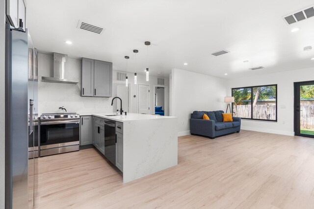 303/305 De Carie, Delray Beach, FL 33444 - kitchen featuring wall chimney range hood, gray cabinetry, stainless steel appliances, and visible vents
