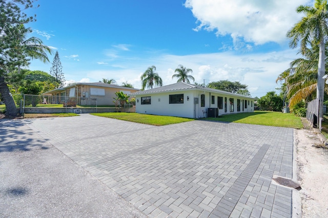 303/305 De Carie, Delray Beach, FL 33444 - view of front of house featuring fence, a front lawn, central AC unit, decorative driveway, and metal roof
