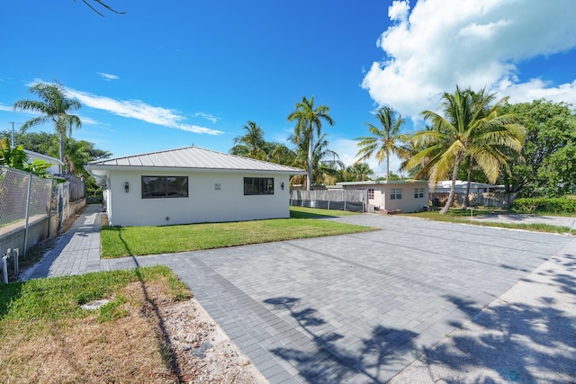 303/305 De Carie, Delray Beach, FL 33444 - rear view of house featuring fence, stucco siding, a standing seam roof, metal roof, and a lawn
