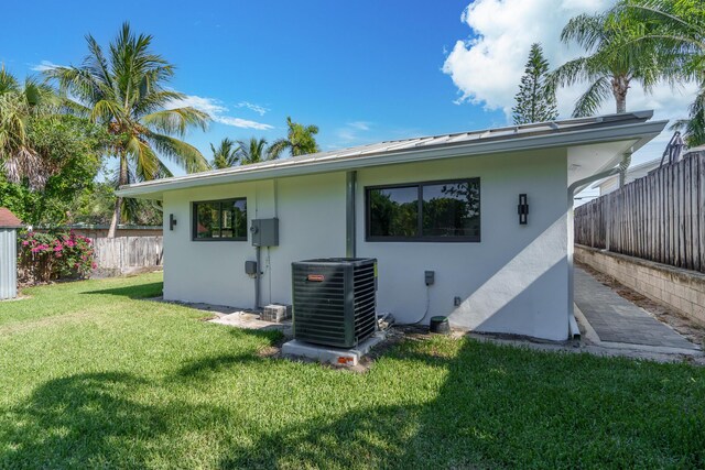 303/305 De Carie, Delray Beach, FL 33444 - back of house featuring stucco siding, central AC unit, fence, and a yard