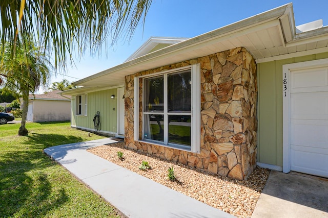 1831 SW Notre Dame Ave, Port Saint Lucie, FL 34953 - property entrance with stone siding, a yard, and board and batten siding