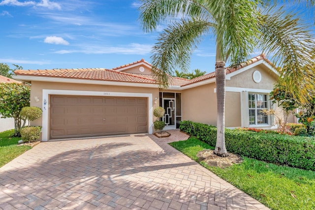 view of front of house with stucco siding, a tile roof, decorative driveway, and a garage
