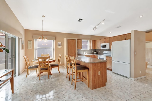 kitchen featuring light tile patterned floors, white appliances, visible vents, and a sink