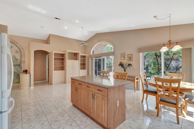 kitchen with freestanding refrigerator, visible vents, ceiling fan, arched walkways, and a center island