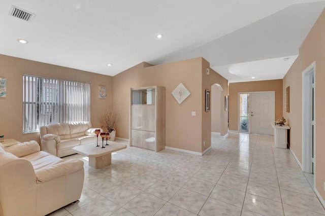 living room featuring lofted ceiling, baseboards, visible vents, light tile patterned flooring, and arched walkways