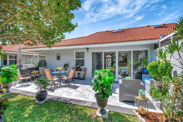 back of property featuring stucco siding, an outdoor living space, a patio area, and a tile roof