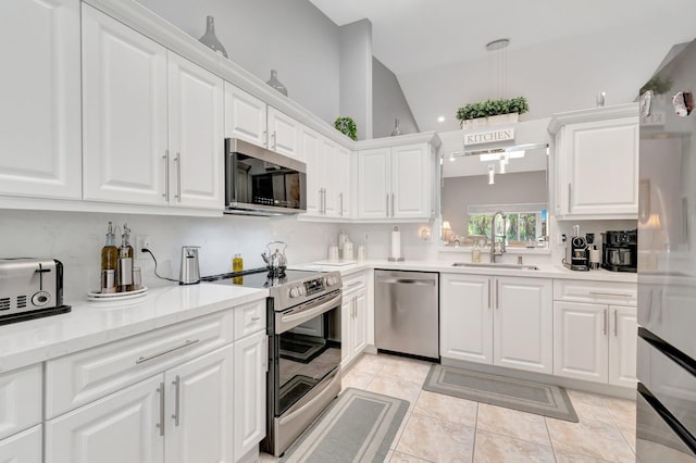 kitchen with lofted ceiling, light countertops, white cabinetry, a sink, and stainless steel appliances
