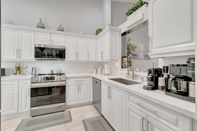 kitchen featuring appliances with stainless steel finishes, a sink, light countertops, white cabinets, and light tile patterned flooring