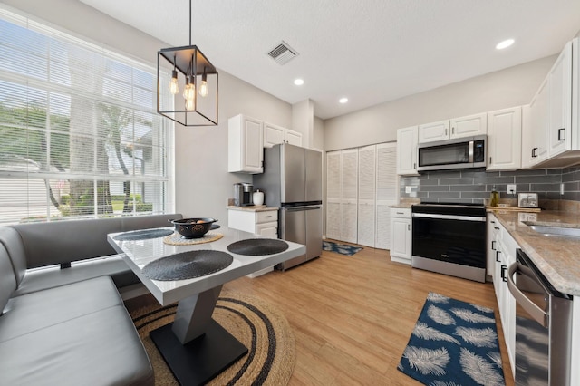 175 Harbor Lake Cir, Greenacres, FL 33413 - kitchen featuring tasteful backsplash, light wood-style flooring, appliances with stainless steel finishes, white cabinetry, and visible vents