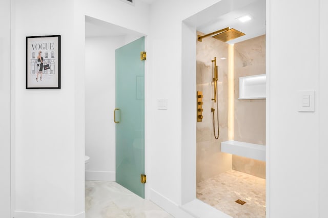bathroom with toilet, a stall shower, and baseboards
