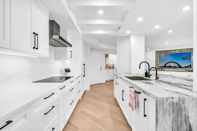 kitchen featuring recessed lighting, wall chimney range hood, black electric cooktop, a sink, and white cabinetry