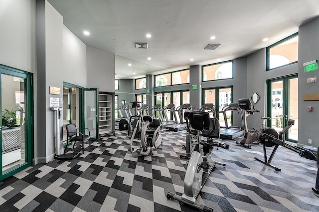 exercise room with a towering ceiling, recessed lighting, visible vents, and dark carpet
