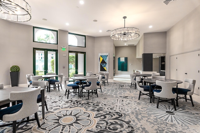dining area with a chandelier, recessed lighting, light carpet, a towering ceiling, and french doors