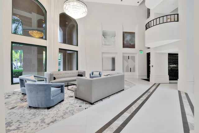 living room with an inviting chandelier, baseboards, tile patterned flooring, and a high ceiling