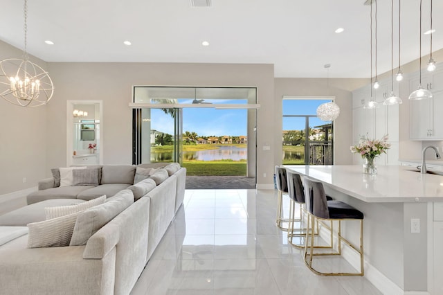 living room with baseboards, recessed lighting, a water view, and a notable chandelier