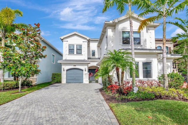 mediterranean / spanish-style home featuring decorative driveway, an attached garage, and stucco siding