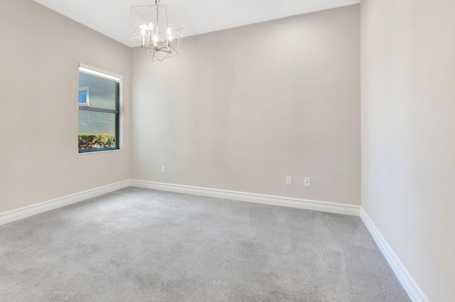 spare room featuring baseboards, carpet, and a chandelier