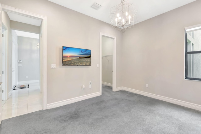 empty room featuring visible vents, carpet, baseboards, and a chandelier