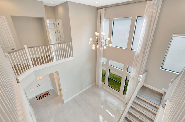 foyer entrance featuring baseboards, a chandelier, and stairway