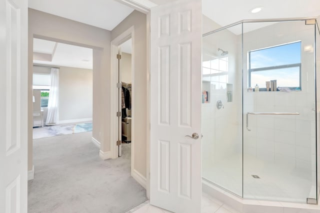 full bathroom featuring baseboards, a shower stall, and a walk in closet
