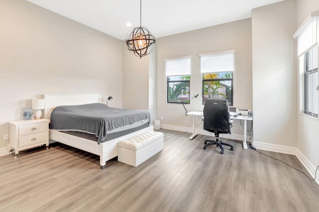 bedroom featuring baseboards, multiple windows, and light wood-style flooring