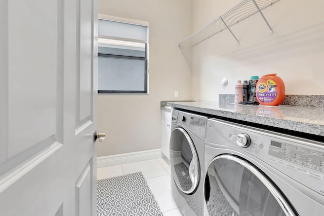 laundry area featuring laundry area, baseboards, washing machine and dryer, and light tile patterned flooring