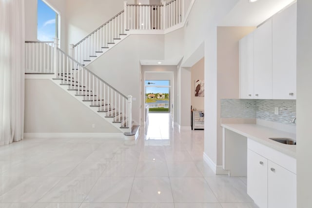 foyer entrance featuring baseboards, a high ceiling, and stairs