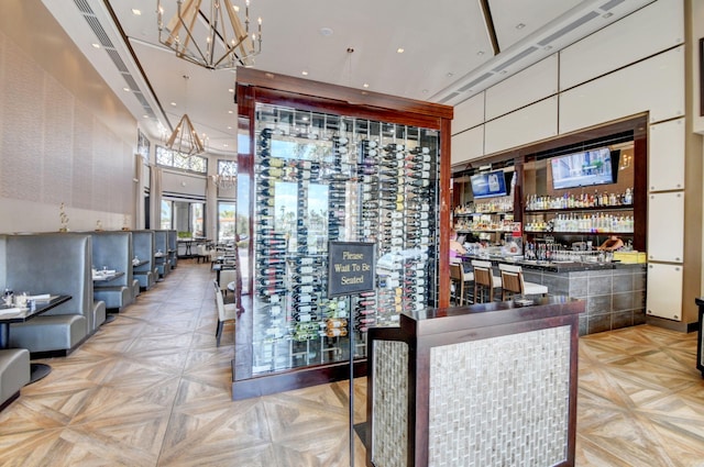 wine cellar with an inviting chandelier, recessed lighting, and a towering ceiling