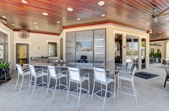 view of patio with ceiling fan, outdoor wet bar, and exterior kitchen