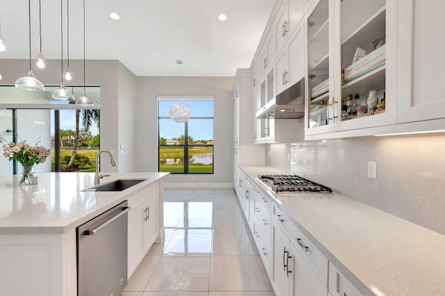 kitchen with appliances with stainless steel finishes, a sink, a kitchen island with sink, light countertops, and under cabinet range hood