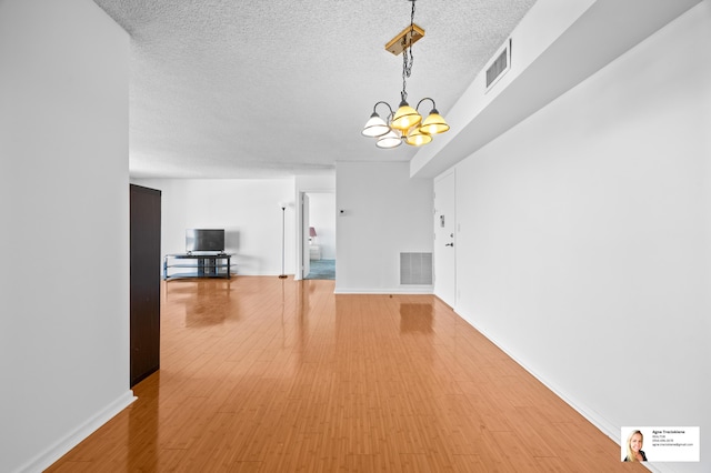 137 Golden Isles Dr Unit 806, Hallandale Beach, FL 33009 - unfurnished living room with a chandelier, a textured ceiling, light wood finished floors, and baseboards