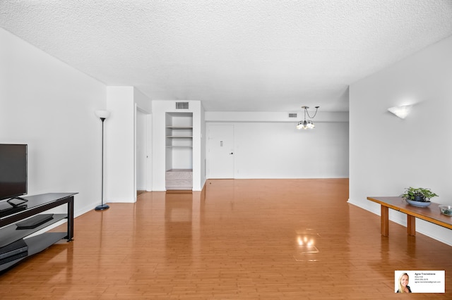 137 Golden Isles Dr Unit 806, Hallandale Beach, FL 33009 - unfurnished living room with light wood-type flooring, a textured ceiling, a chandelier, and baseboards