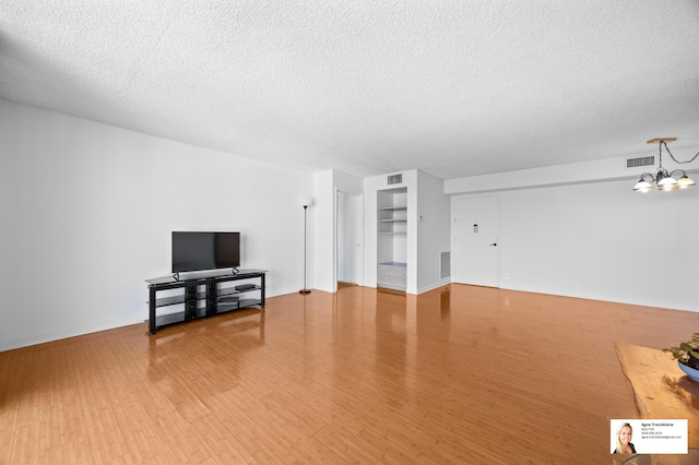 137 Golden Isles Dr Unit 806, Hallandale Beach, FL 33009 - unfurnished living room with a textured ceiling, light wood-type flooring, and a chandelier