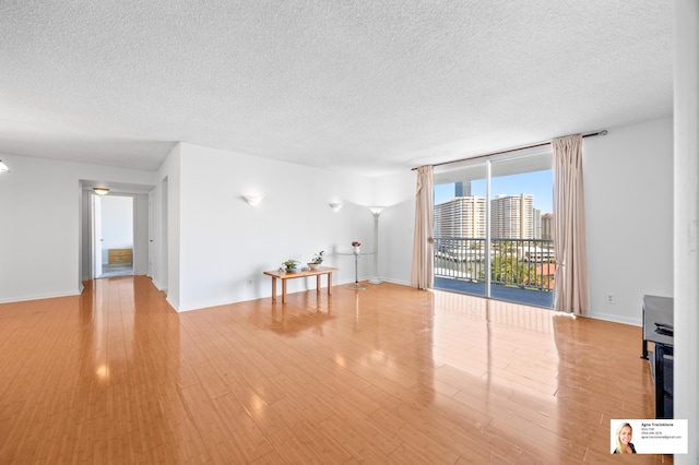 137 Golden Isles Dr Unit 806, Hallandale Beach, FL 33009 - unfurnished living room with a textured ceiling, floor to ceiling windows, light wood-type flooring, and baseboards