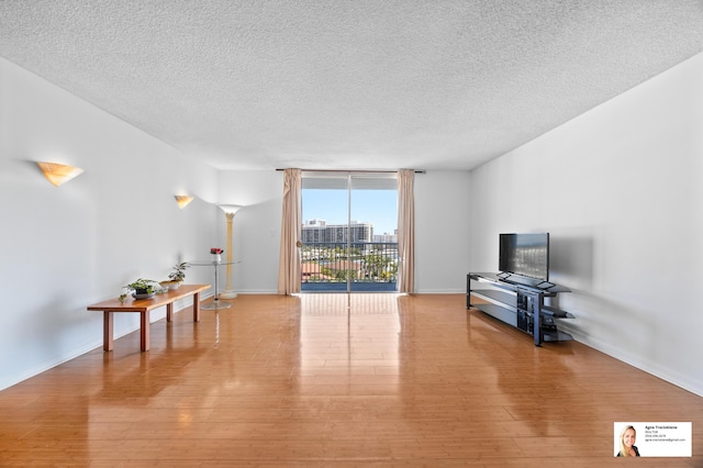 137 Golden Isles Dr Unit 806, Hallandale Beach, FL 33009 - living area with a textured ceiling, light wood finished floors, and baseboards