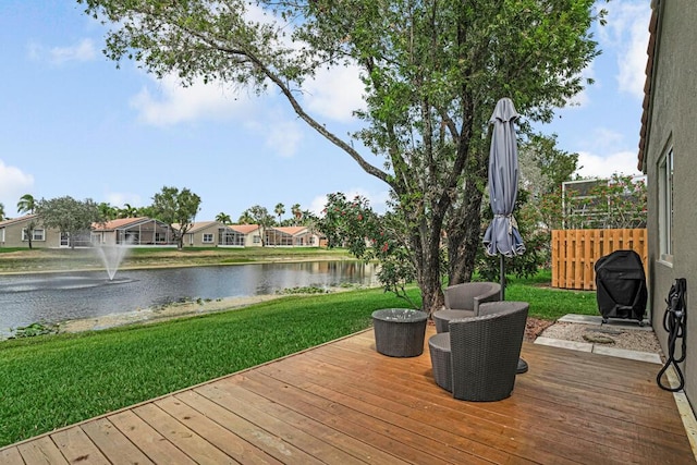 wooden deck with a water view, a yard, and a grill